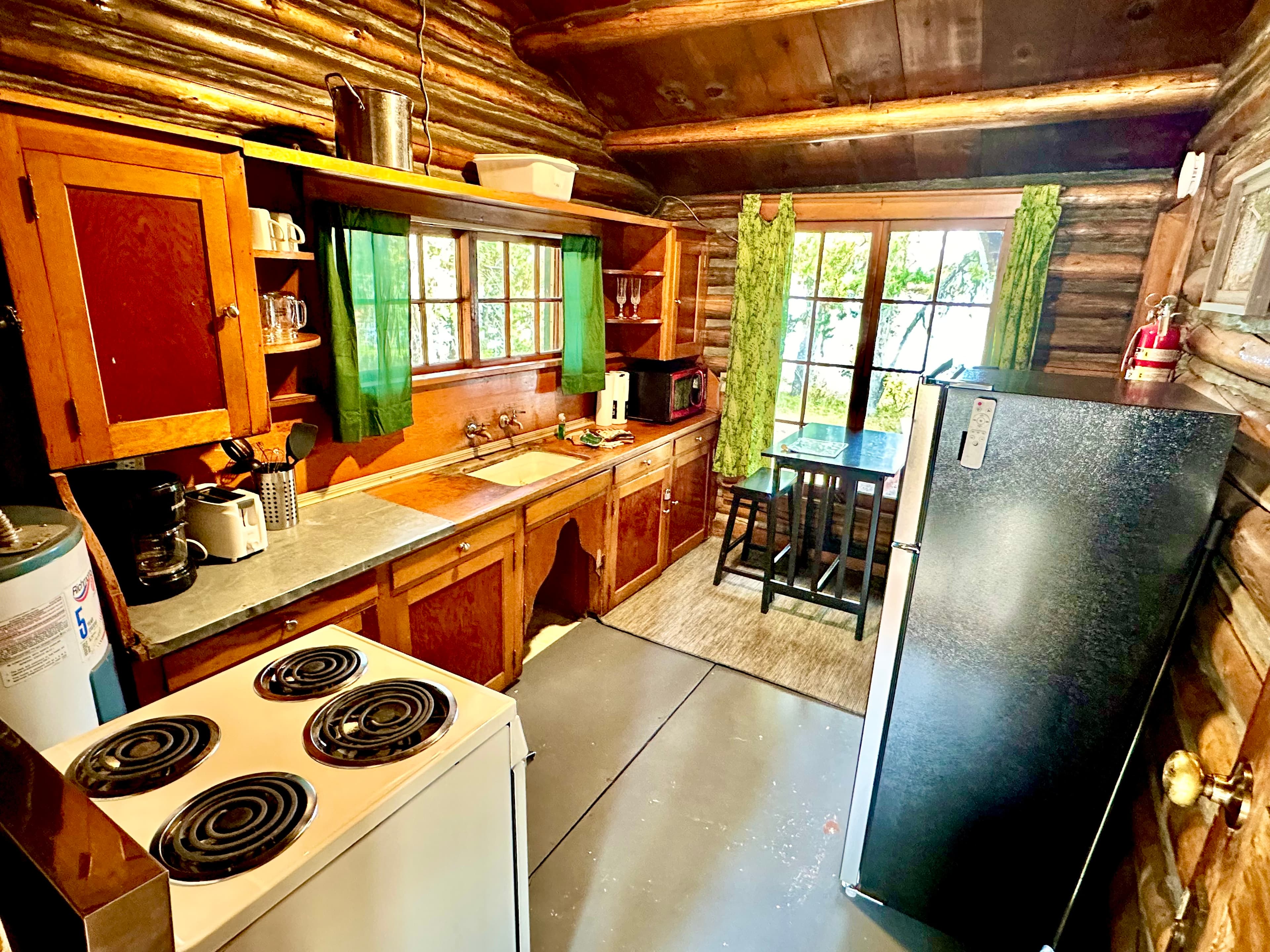 Cozy log cabin kitchen featuring wooden cabinets, a small dining table, and modern appliances.