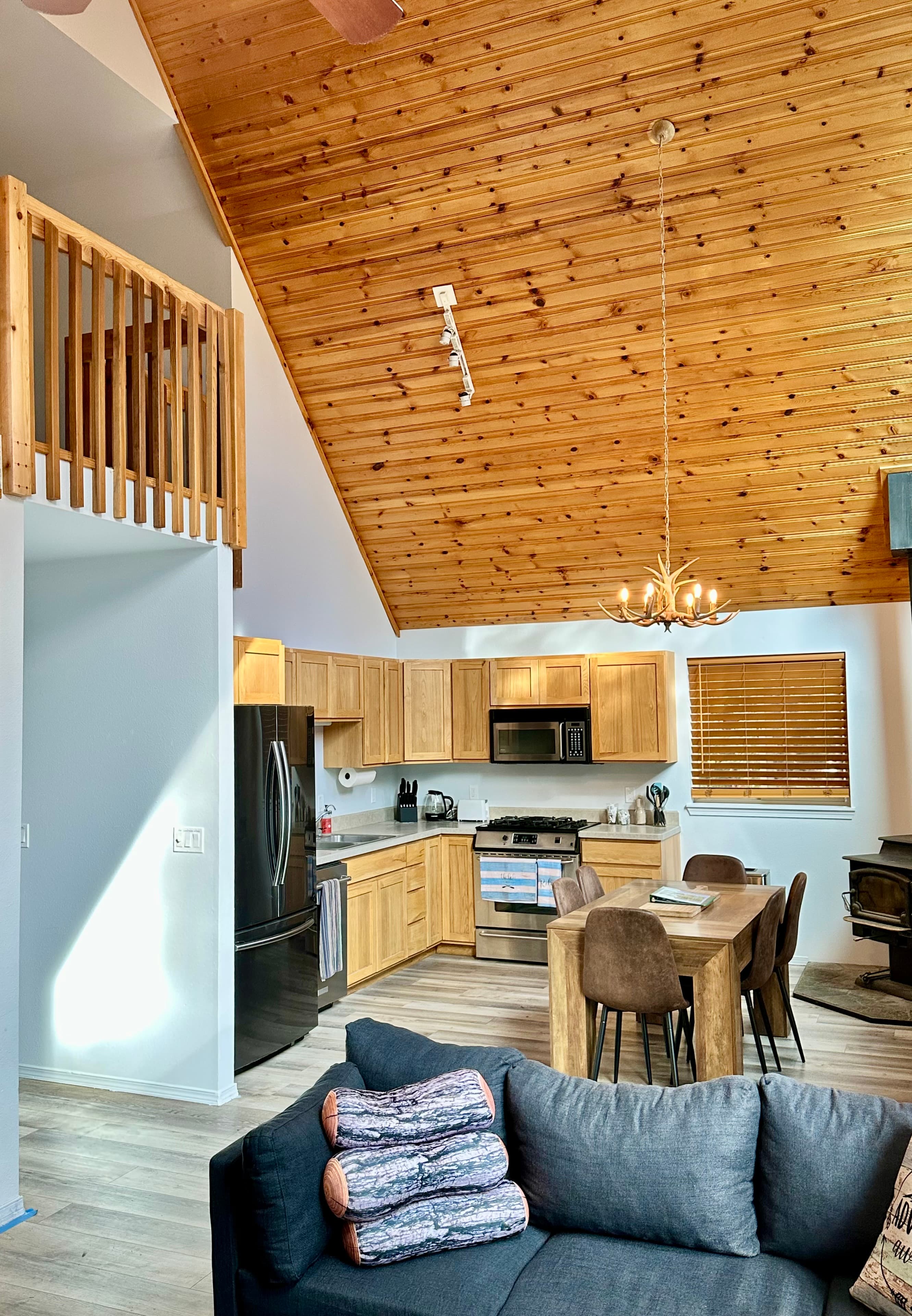A bright, modern kitchen and living area with high wooden ceilings and stylish furnishings.
