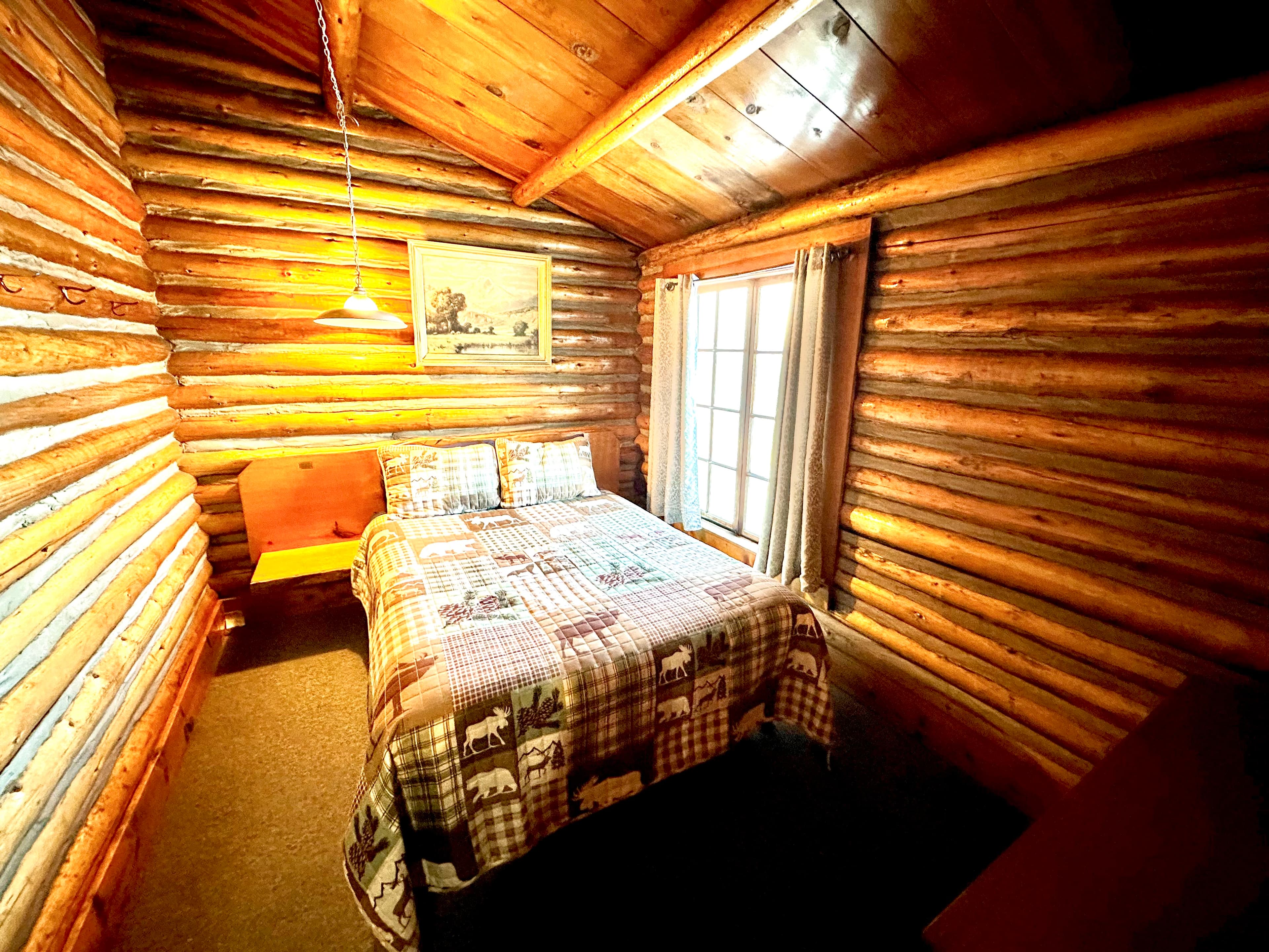 Cozy log cabin bedroom featuring a double bed with a patterned blanket and wooden decor.
