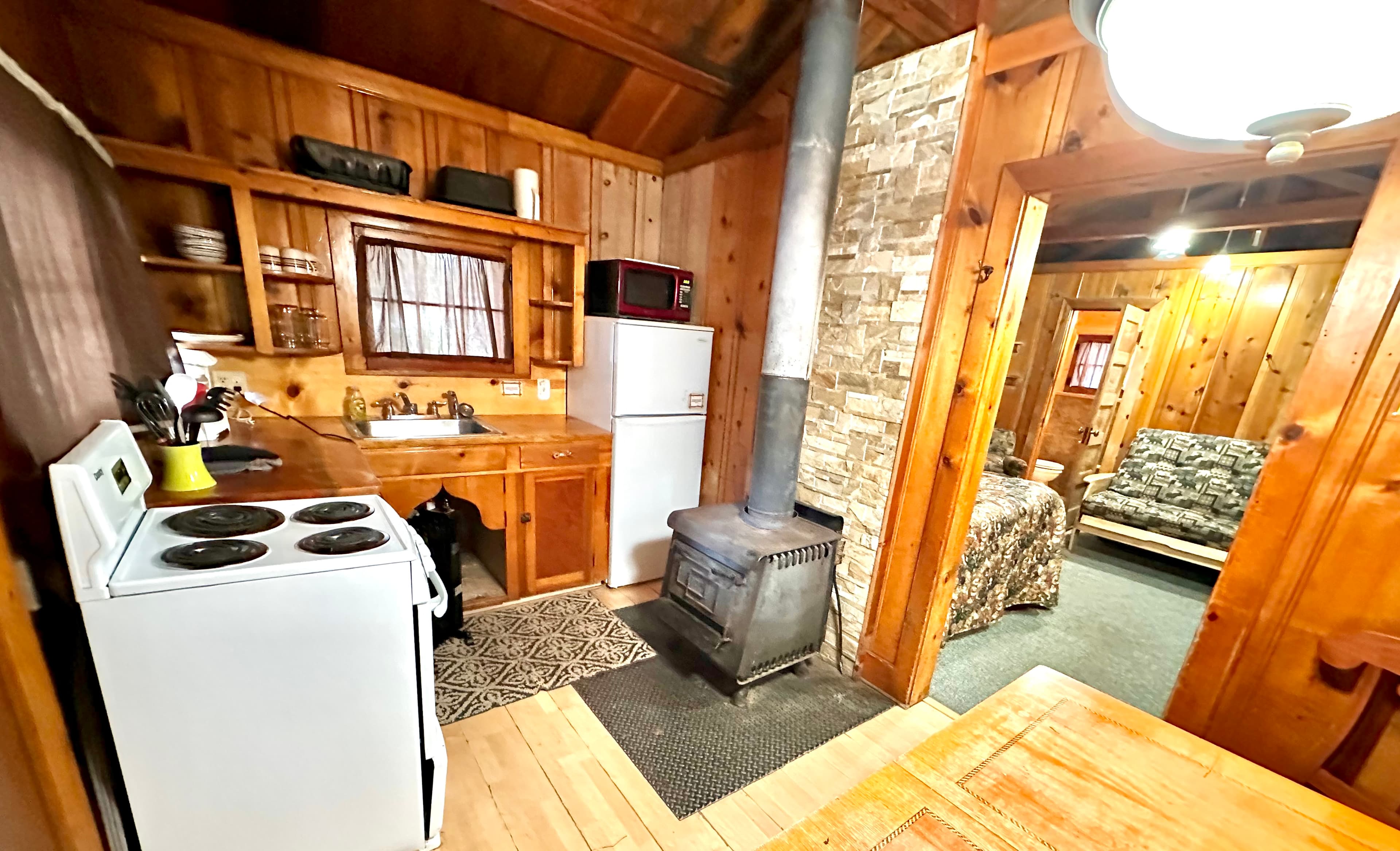 Cozy wooden cabin kitchen with stove, fridge, and dining area.