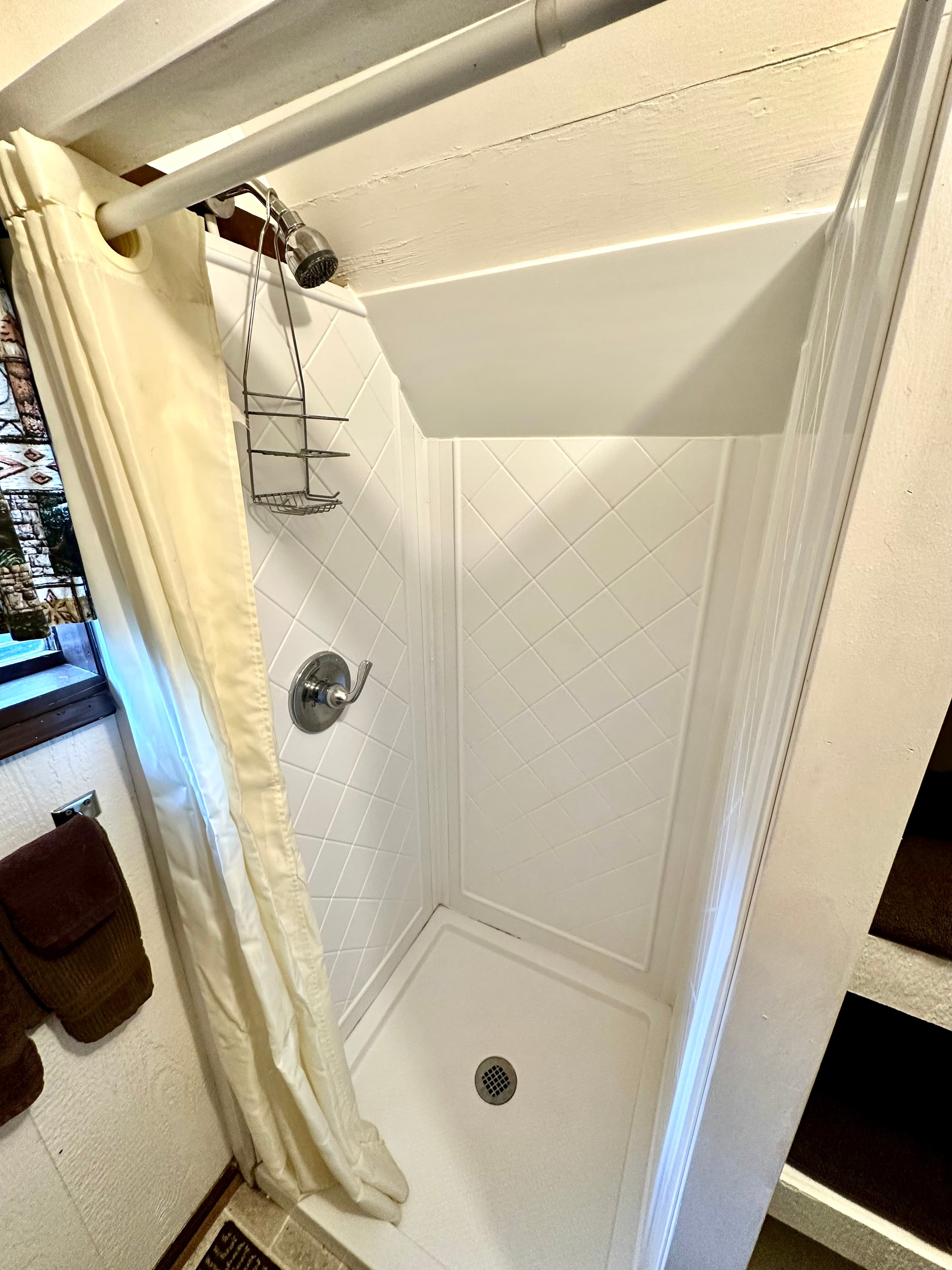 A clean, white shower stall with a curtain and showerhead.