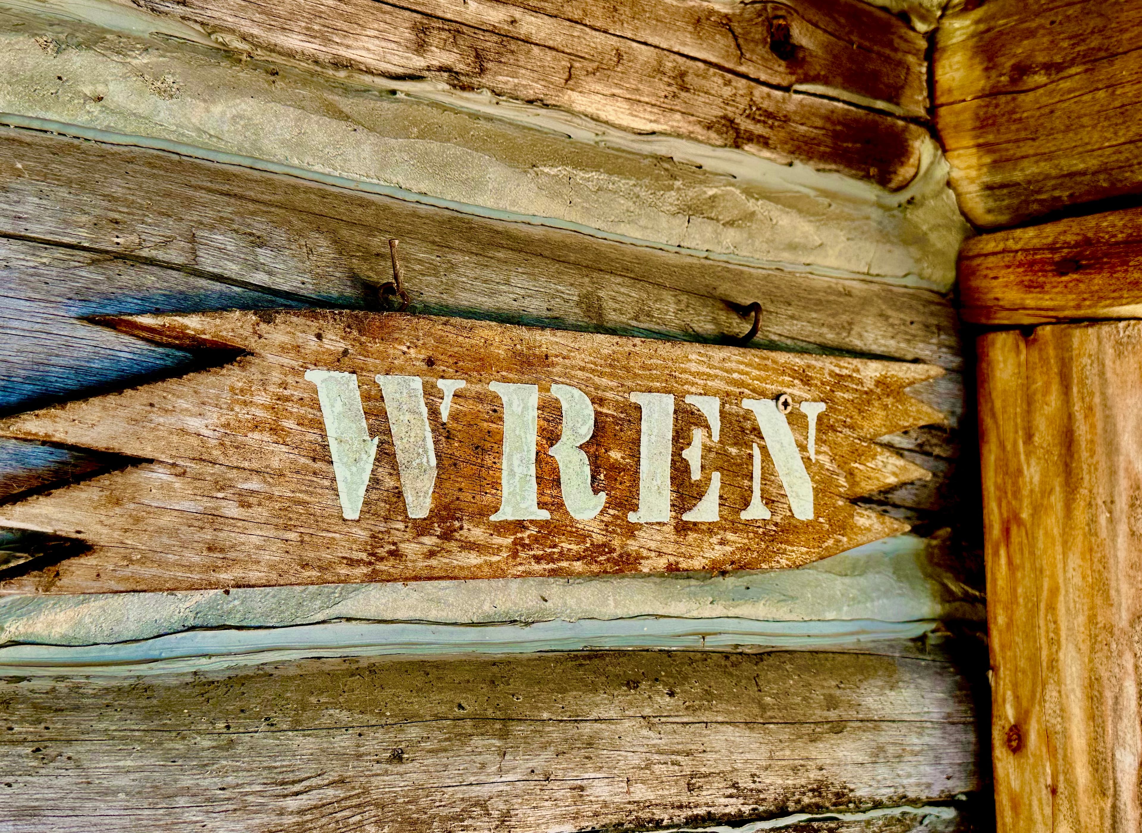 A wooden sign with the word "WREN" engraved on it.