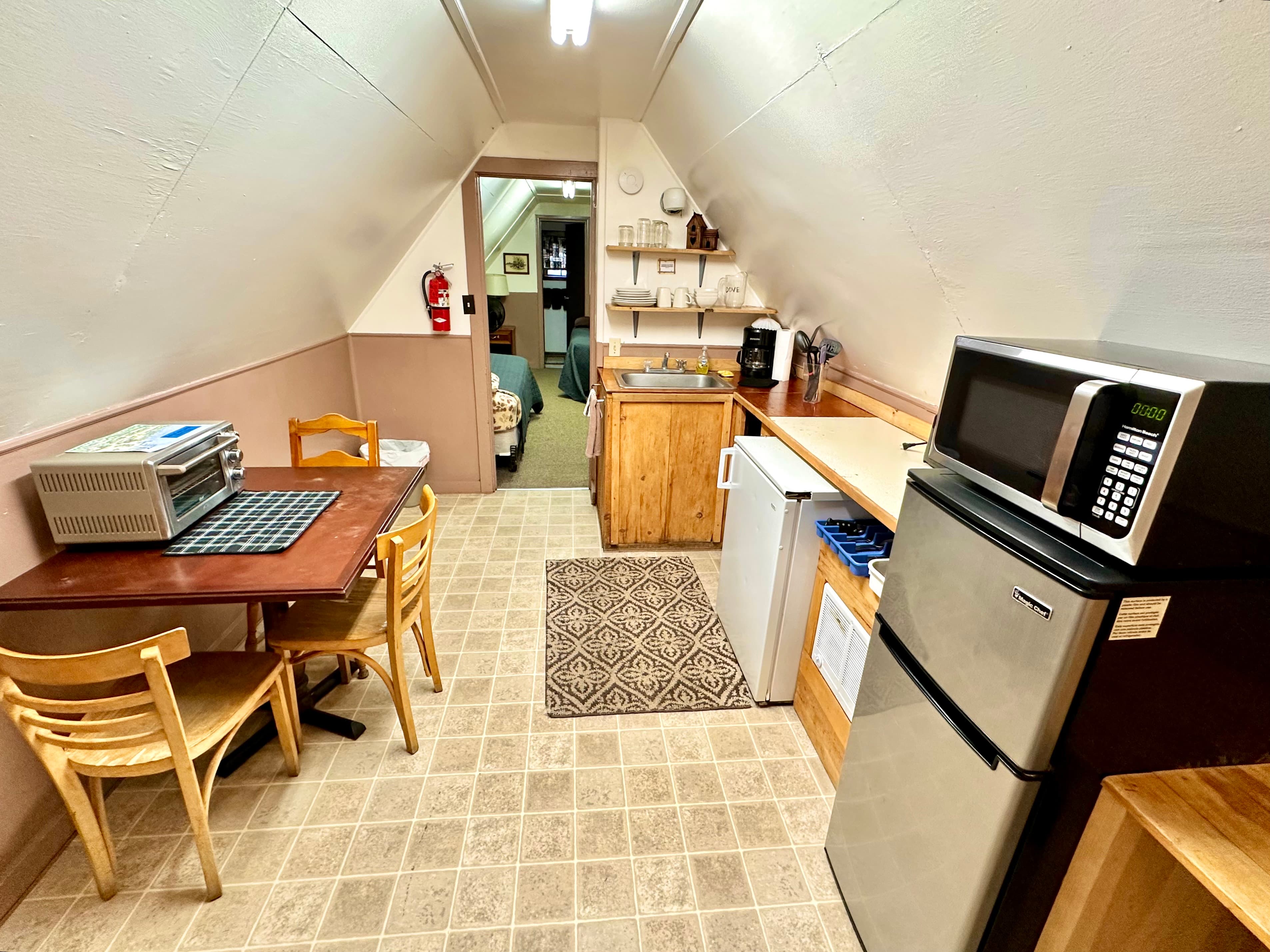 A compact kitchen with a dining table, appliances, and an inviting decor in an attic space.