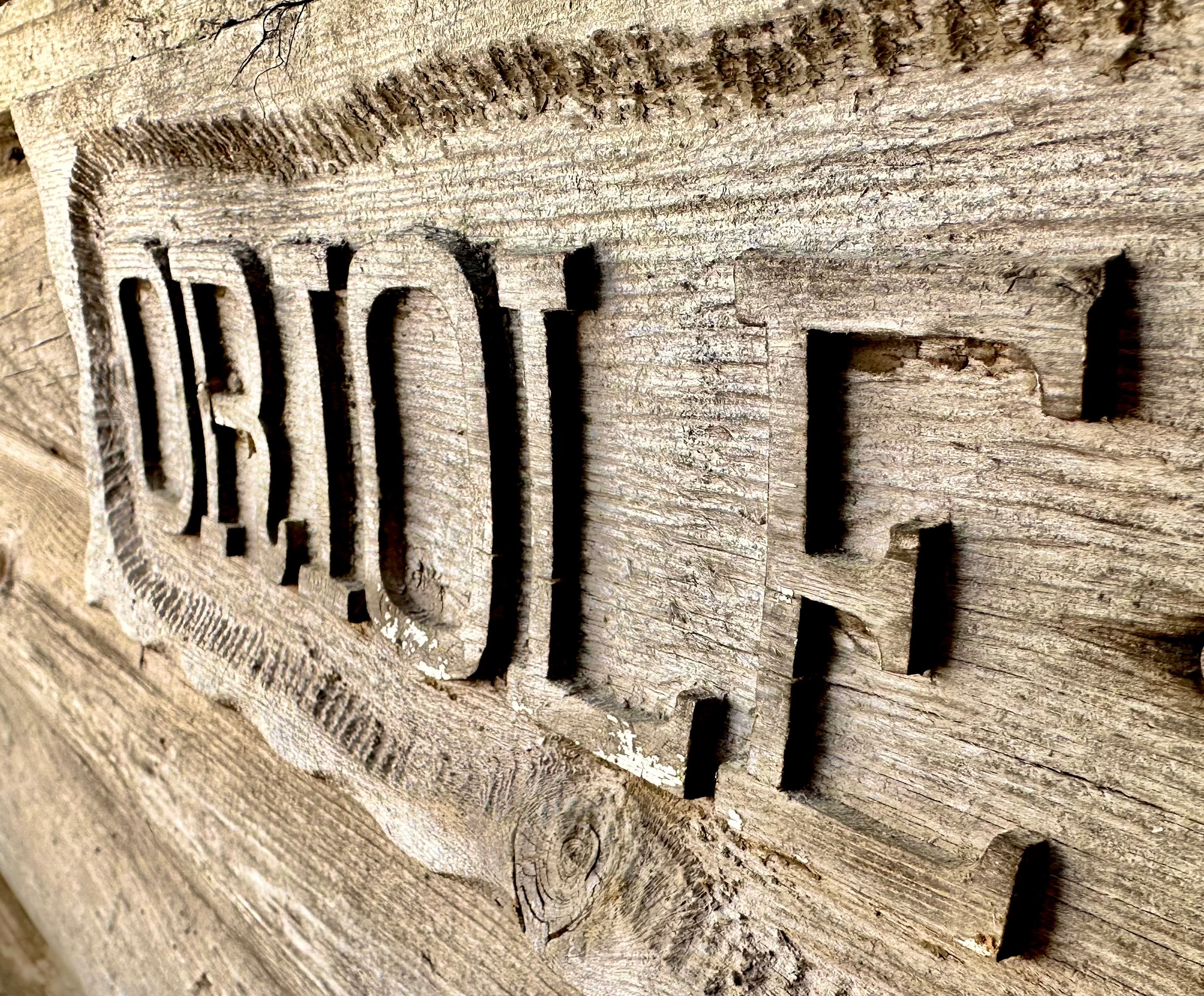 Close-up of carved wooden lettering spelling "ORJOLF."