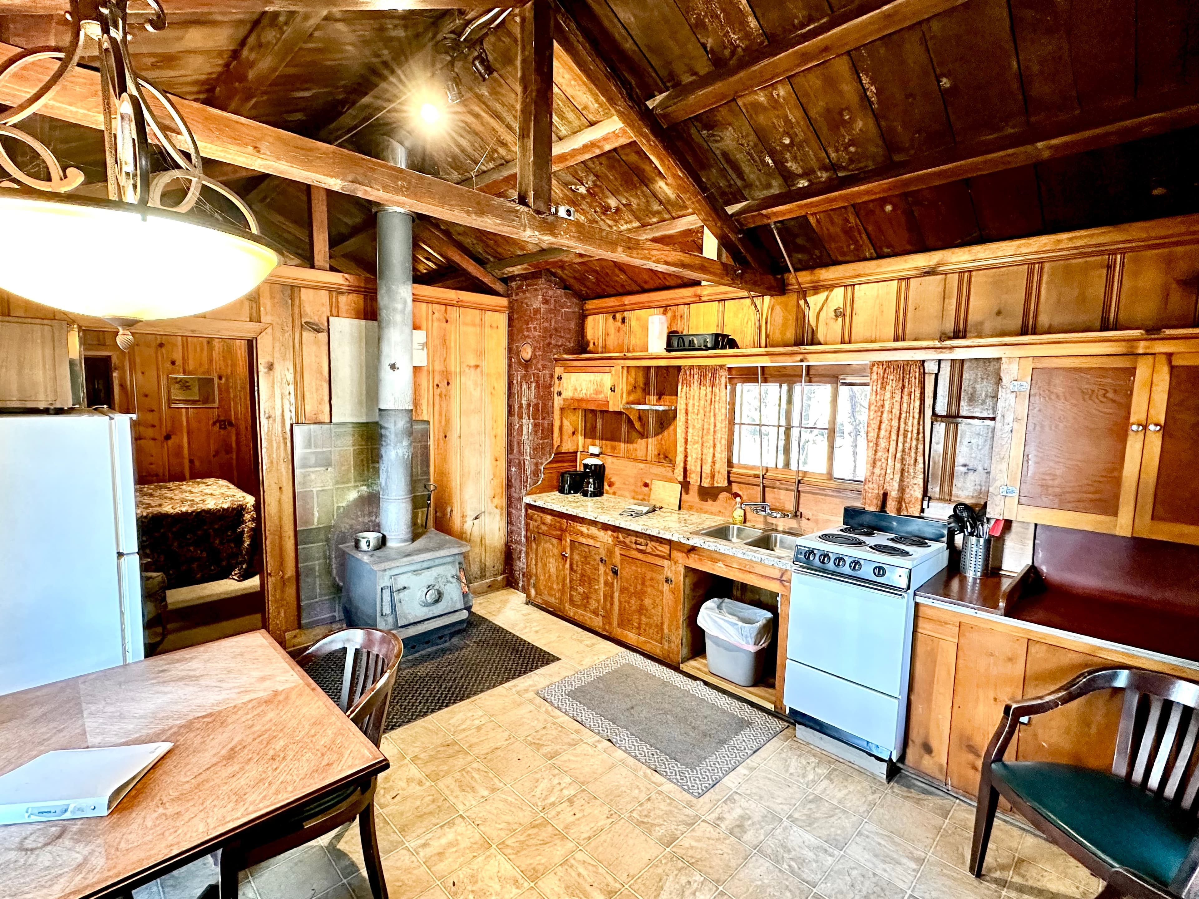 Cozy wooden kitchen with a dining area, stove, and natural light.